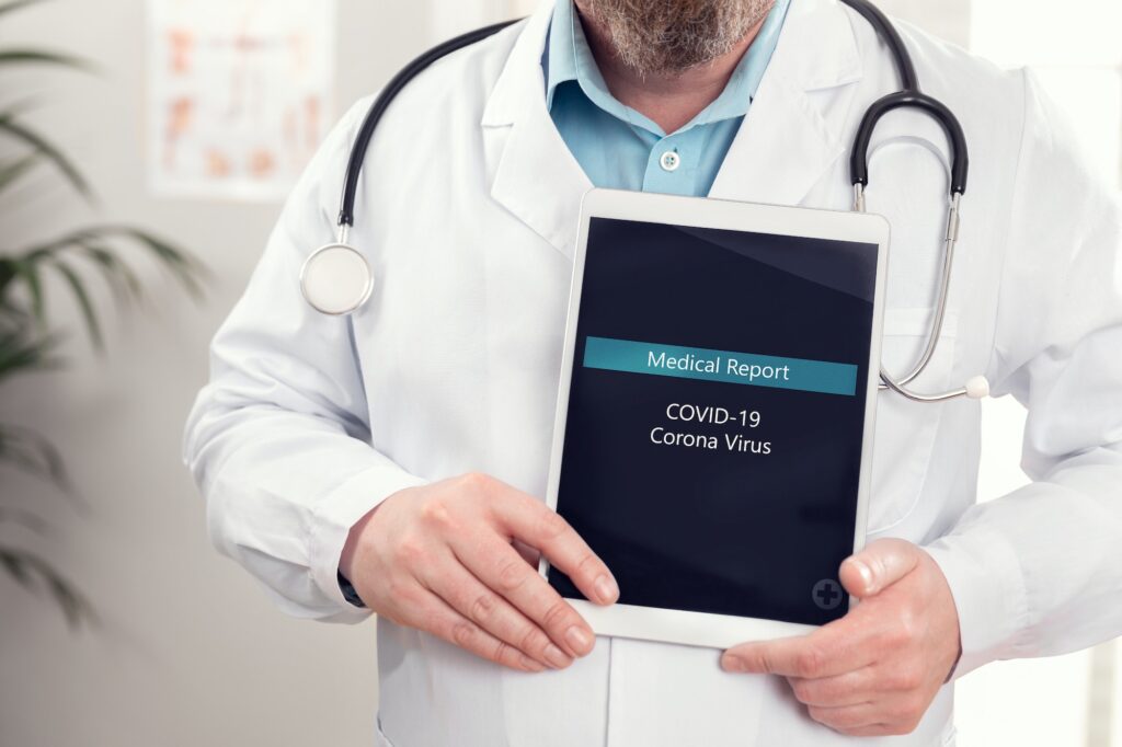 Male doctor showing medical covid-19 corona virus report on a tablet